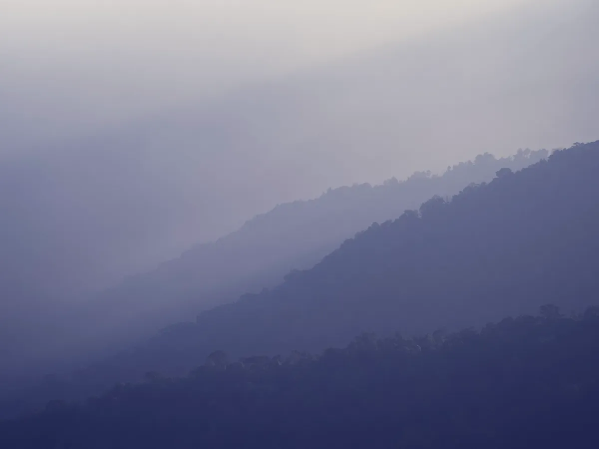 Layered blue mountain ridges fading into haze below the Kuwohi observation tower